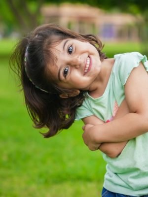 Happy cute little indian girl child standing having fun at summer park or garden.